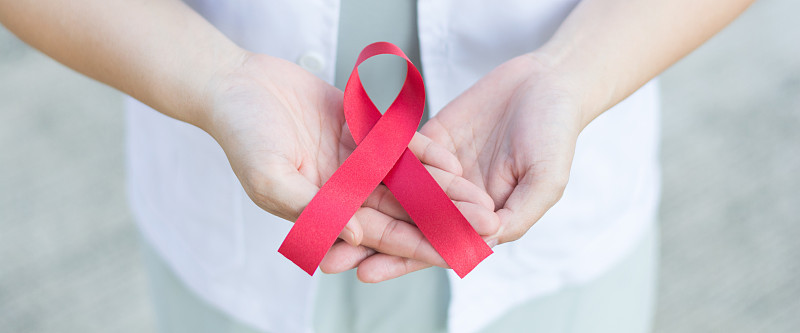 女医生手里拿着红色的艾滋病丝带。全国献血者月。12月世界艾滋病日的象征概念是提高对艾滋病毒感染者健康