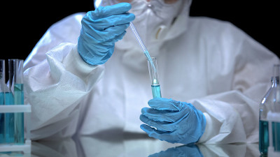 化学实验室助理从试管中提取蓝色液体样本，做实验
