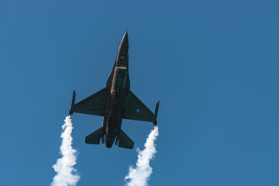 F-16战斗机在蓝天的背景下带着烟雾飞行。