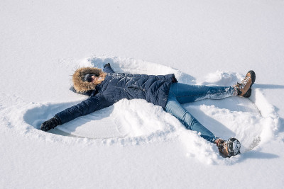 快乐的女人在冬天做雪天使