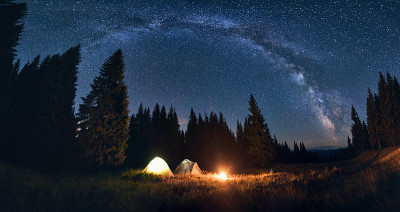 夜间露营在山谷大松树。燃烧的篝火和帐篷下，明亮的星空下，银河