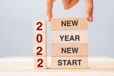 桌子背景上，商人手拿木块，上面写着“2022年新年新开始”。决心，策略，解决方案，商务和度假概念