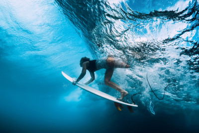 冲浪潜水水下。冲浪女孩在巨浪下潜水