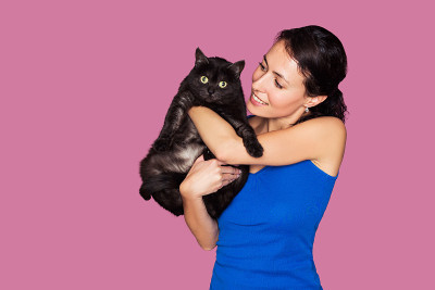 漂亮的年轻女子抱着孤立的黑猫粉红色