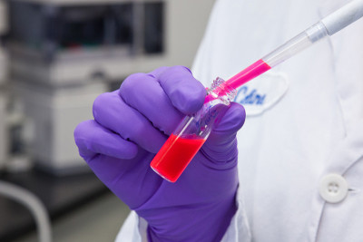 科学家用移液管将粉红色液体注入小瓶