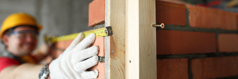 建筑工在砖墙上用卷尺测量