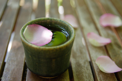 木桌上放着粉红玫瑰花瓣和茶杯