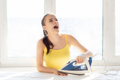 不小心操作电器的后果。一位年轻妇女在烫衣服时被熨斗烫到了手