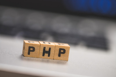 PHP编程网络语言:字母“PHP”的木制立方体躺在笔记本电脑上，概念