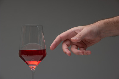 白人男性伸手去抓半满的高酒杯。工作室拍摄，没有人