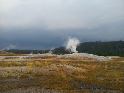 Old Faithful Geyser erupting in stormy skies