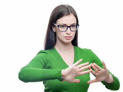年轻的黑发女人用怀疑的表情表示拒绝。她戴着一副眼镜，穿着一件绿色的衬衫。工作室肖像孤立在白色高分辨率