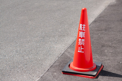 街上有一个红色的尖塔，上面用日语写着“禁止停车”。