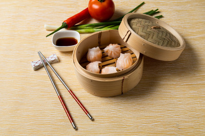 蒸虾饺，配酱料和筷子。中国传统美食的概念。饺子点心在竹蒸笼内用文字抄写空间。亚洲食物背景