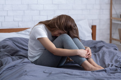 不幸的年轻女子患有抑郁症，躲在家里的床上哭泣