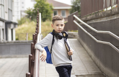 一名小学生背着书包微笑着站在家门口