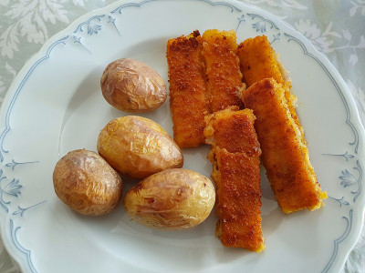 在白色盘子上夹上土豆和鱼条。食物,关闭。