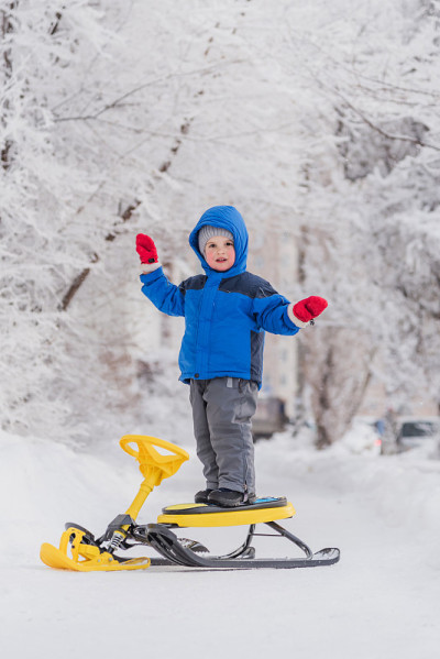 冬天，一个小孩站在雪地摩托上