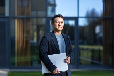肖像英俊的亚洲人大学学院教师，商人，科学家或教育家。站在现代办公中心或校园背景，双臂交叉站在户外，对