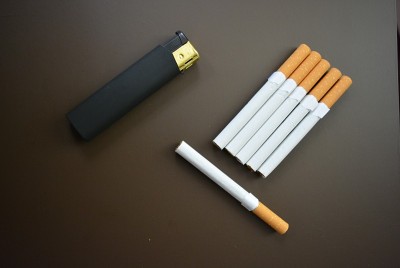 漂亮的香烟与黑色打火机在棕色的黑色背景。