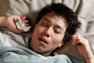 一名亚洲男子在床上睡觉，饱受流感之苦