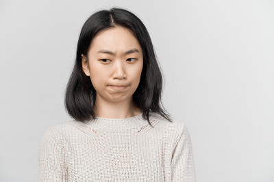 沉思的漂亮的年轻女性看起来可疑的一边