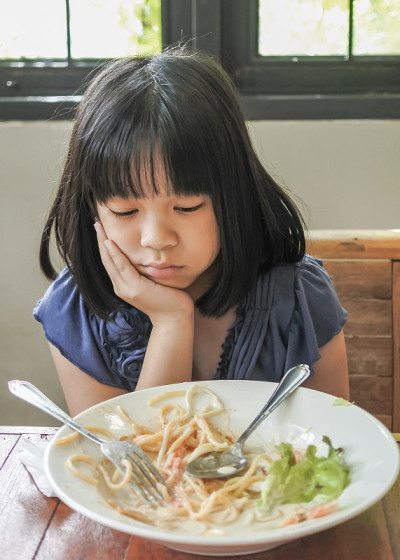 儿童营养不良饮食失调的概念与不快乐的亚洲女孩孩子对食物感到厌倦，食欲下降，没有饥饿的习惯在学校食堂，