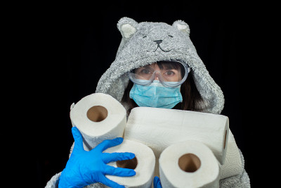 病毒。一位戴着医用口罩、穿着浴袍的妇女手里拿着卫生纸。