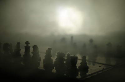 棋牌游戏的经营理念和竞争理念以及战略理念。象棋人物在烟雾缭绕的黑暗背景上。