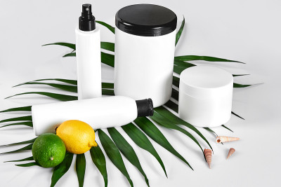 家用天然化妆品。俯视图瓶霜，洗发香波，精油面膜，新鲜酸橙果，绿叶装饰，白色背景
