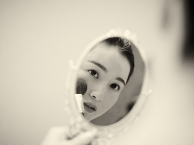 年轻的亚洲女子在化妆时看着镜子
