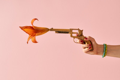 一名女子的手从金色的假枪中射出一朵花