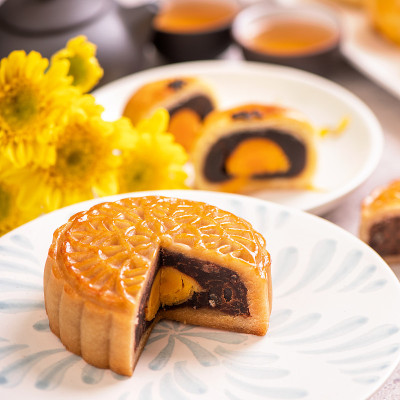 中秋节传统食品概念-美丽的切割月饼上的蓝色图案盘在白色的背景与花。
