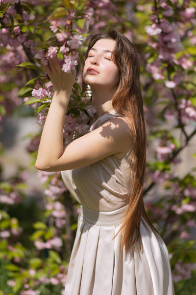 美丽的年轻女子在樱花盛开的花园里摆姿势