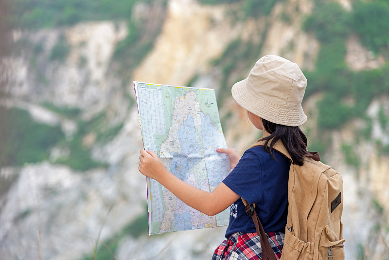 儿童亚洲女孩拿着地图和磁罗盘旅行背包站在山上教育自然。旅游的概念