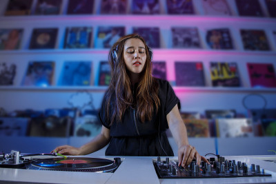 墨西哥dj女孩混合音乐在一个唱片店与转盘和黑胶唱片，复古的概念