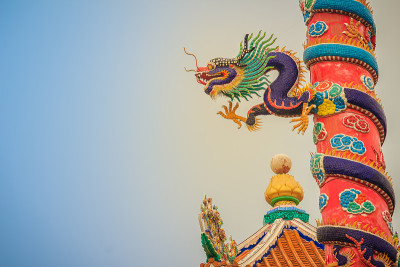 五颜六色的中国龙绕红柱雕像。在中国公共寺庙中，寺庙柱周围雕刻着美丽的龙像。