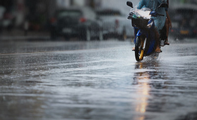 A couple with raincoat on a motorbike during hard 