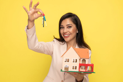 enthusiastic young woman holding keys and building