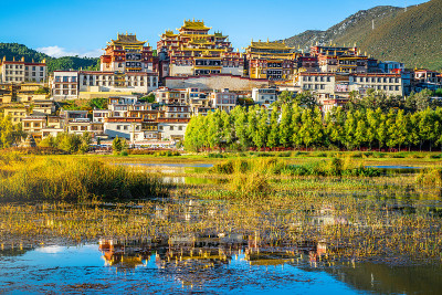 美丽的风景松赞林寺与水反射日落和戏剧性的光在中国云南香格里拉