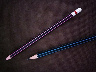 两支铅笔孤立在深棕色的布背景上