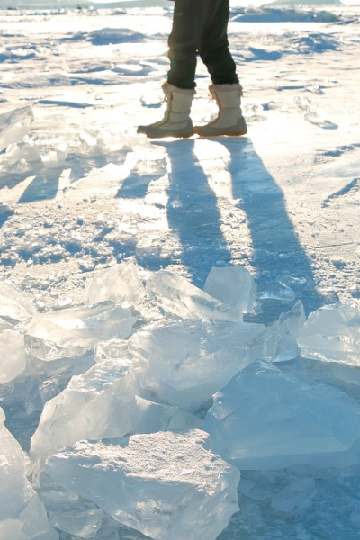 冬天，游客们穿着雪地靴沿着结冰的贝加尔湖行走。