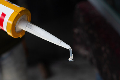男士的手用硅胶胶与胶把镜子与铝连接起来。