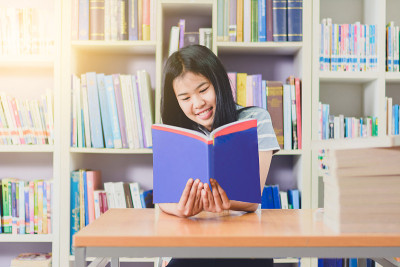 聪明的亚洲学生在大学图书馆挑选书籍阅读和研究的肖像