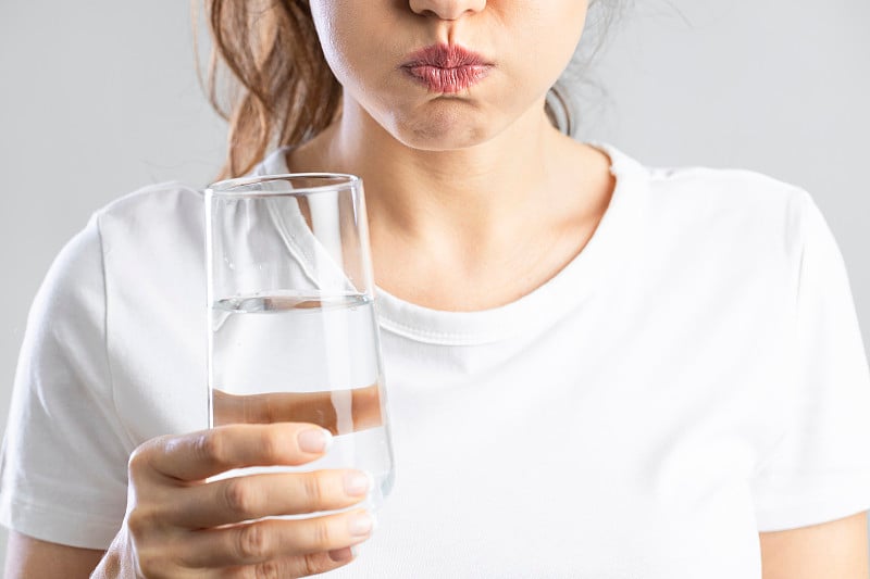 一个年轻女子正在用一杯水漱口