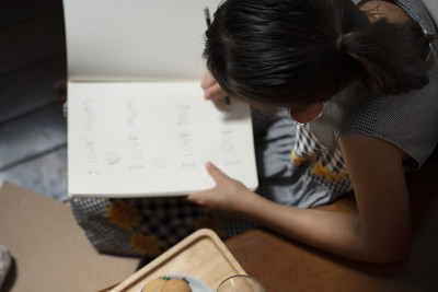 小女孩在家里的楼梯边写书边吃饼干。