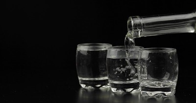 在黑色的背景下，从瓶子中倒出几杯伏特加到玻璃杯中