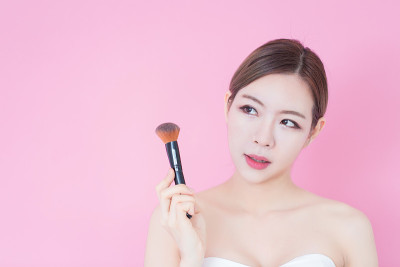年轻美丽的白种人妇女使用化妆刷粉