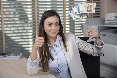 女商人展示金钱雕像，商业成功，竖起大拇指