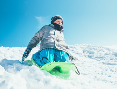 快乐的男孩用雪橇从雪山上滑下来。冬季户外活动